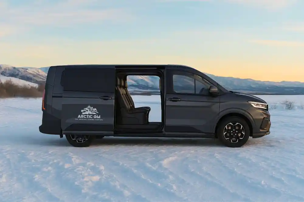 Black van parked on frozen landscape with mountains beyond