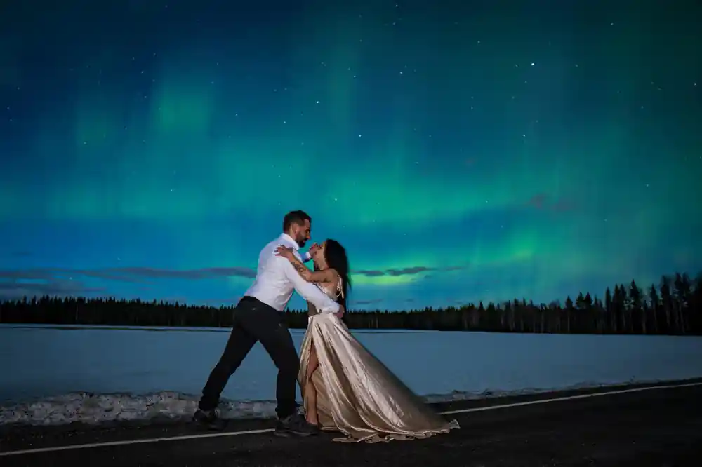 Bride and groom dancing under green aurora borealis