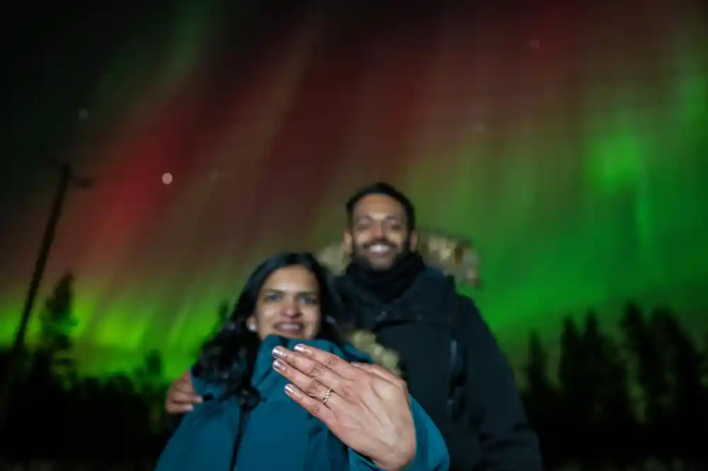 Couple with engagement ring under aurora borealis