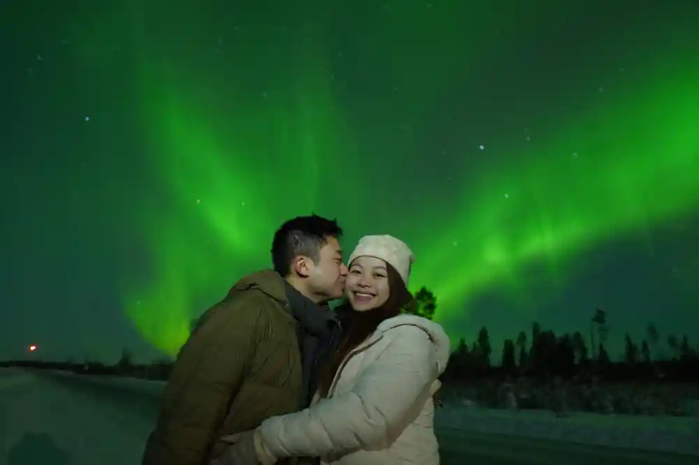 Couple kissing under aurora borealis at night