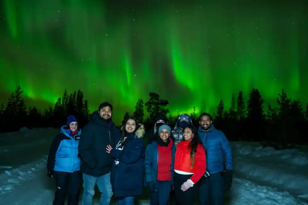 Group of six people under bright aurora borealis