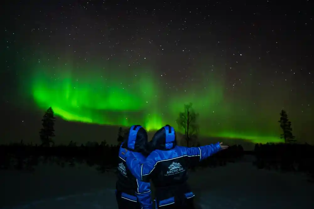 Person in blue jacket under bright aurora