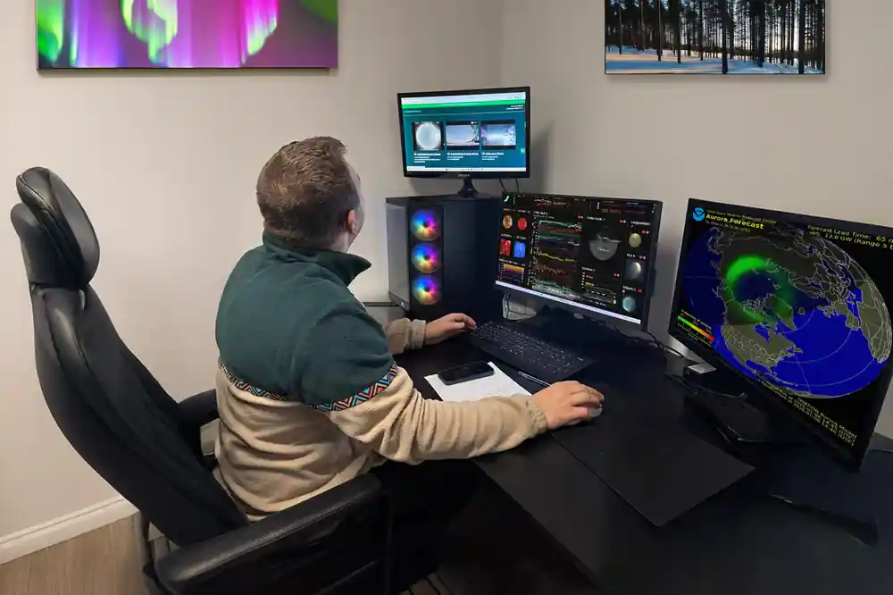 Person at computer workstation with aurora monitoring displays