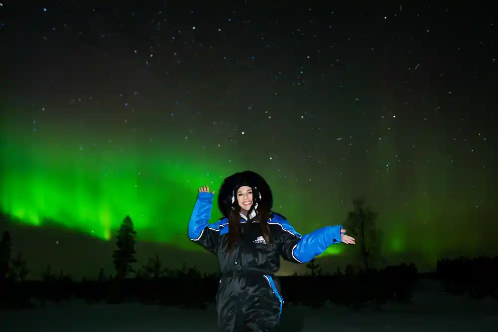 Person in winter gear under aurora borealis